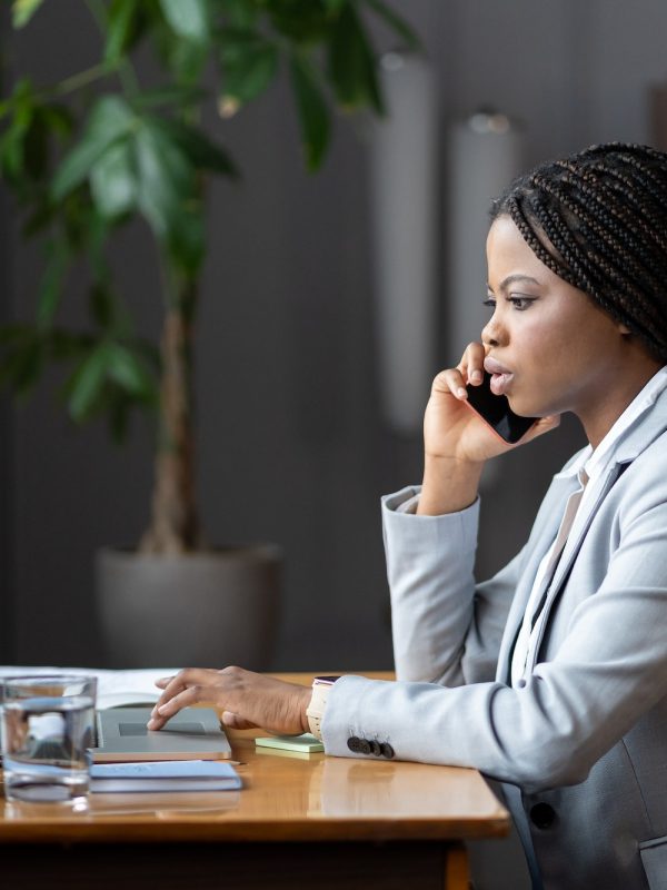 afro-female-business-consultant-interacting-with-client-over-phone-and-entering-data-on-laptop.jpg